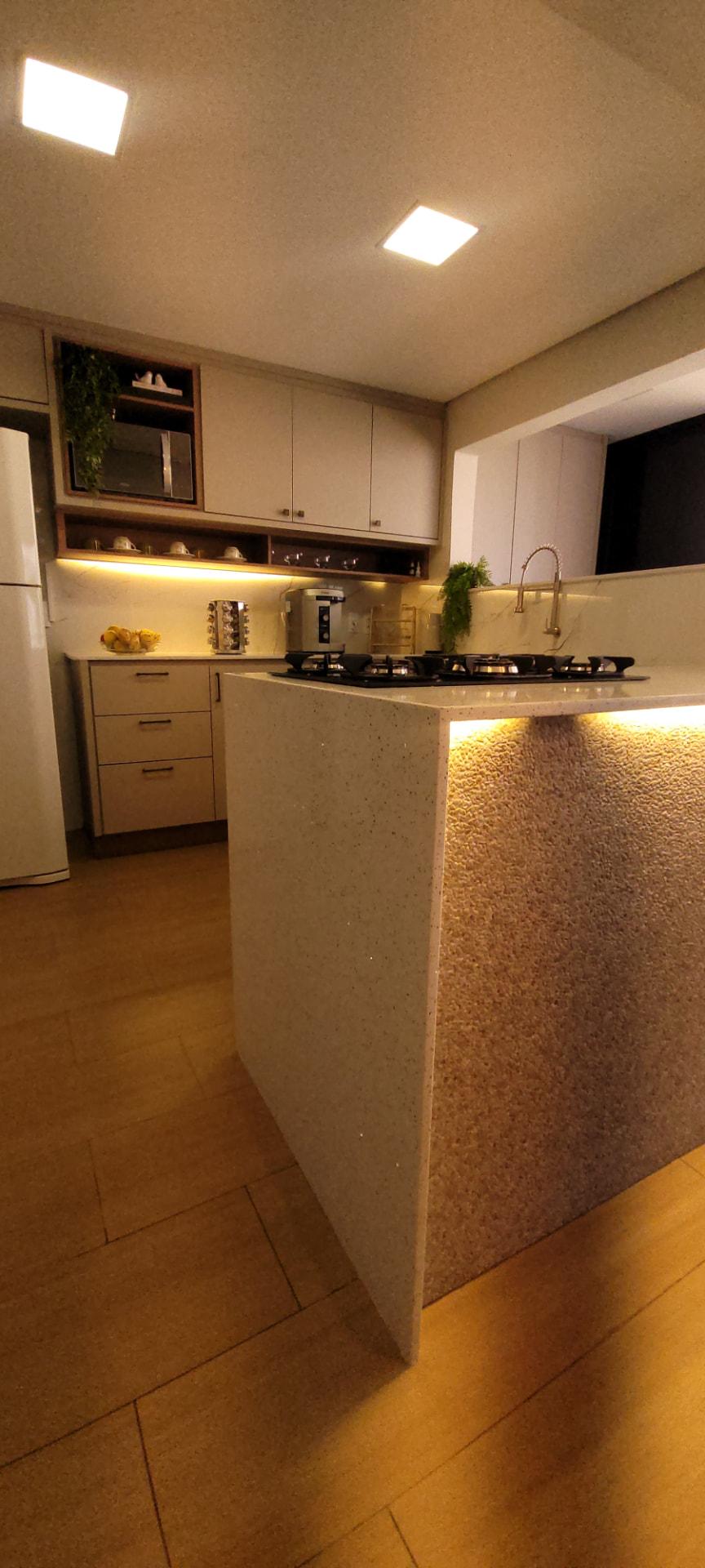 Detalhe da bancada em quartzo e nichos iluminados da cozinha reformada